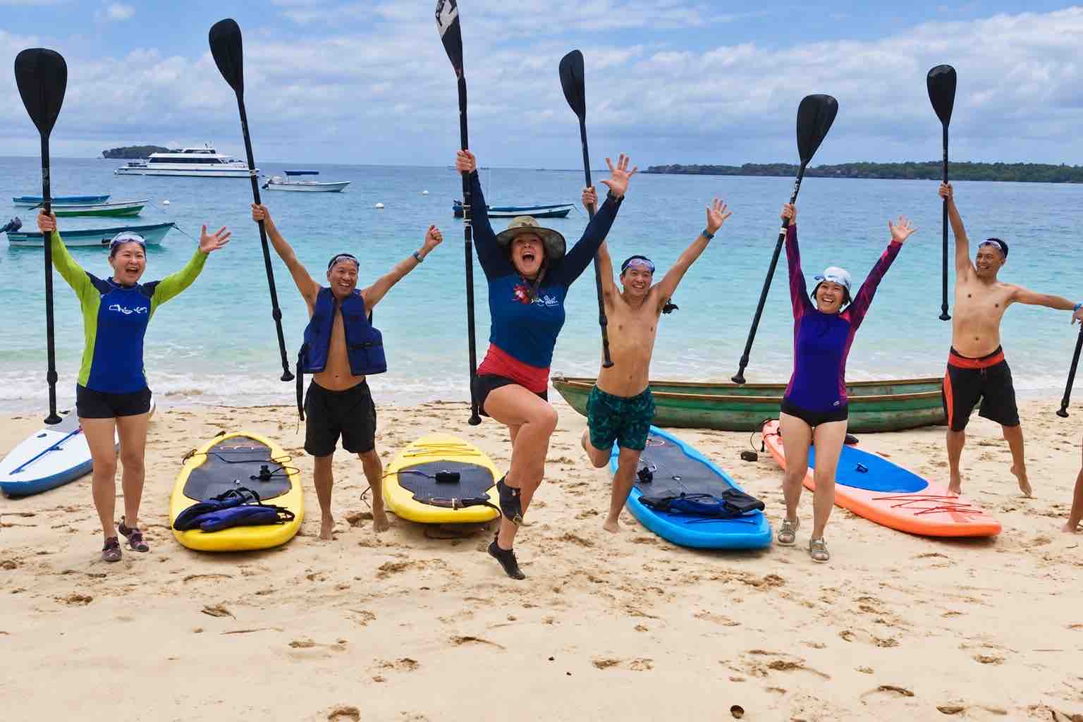 Guests posing with paddleboards on the beach during a Pearl Islands Panama Day Trip