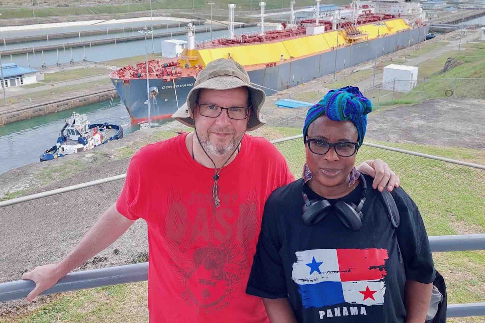 Couple at the Agua Clara viewing area with a cargo ship in the locks behind them on the Ocean to Ocean Panama Canal Tour
