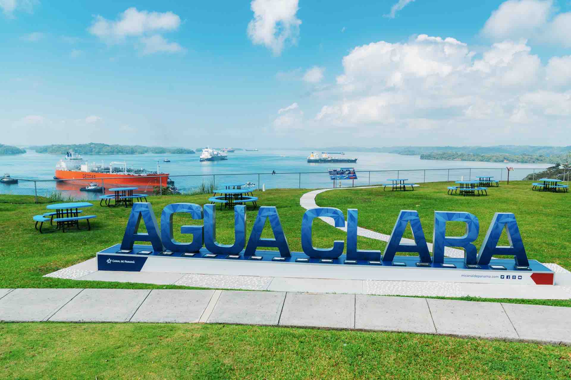Agua Clara sign on a grassy viewing area overlooking ships on the Panama Canal on the Ocean to Ocean Panama Canal Tour