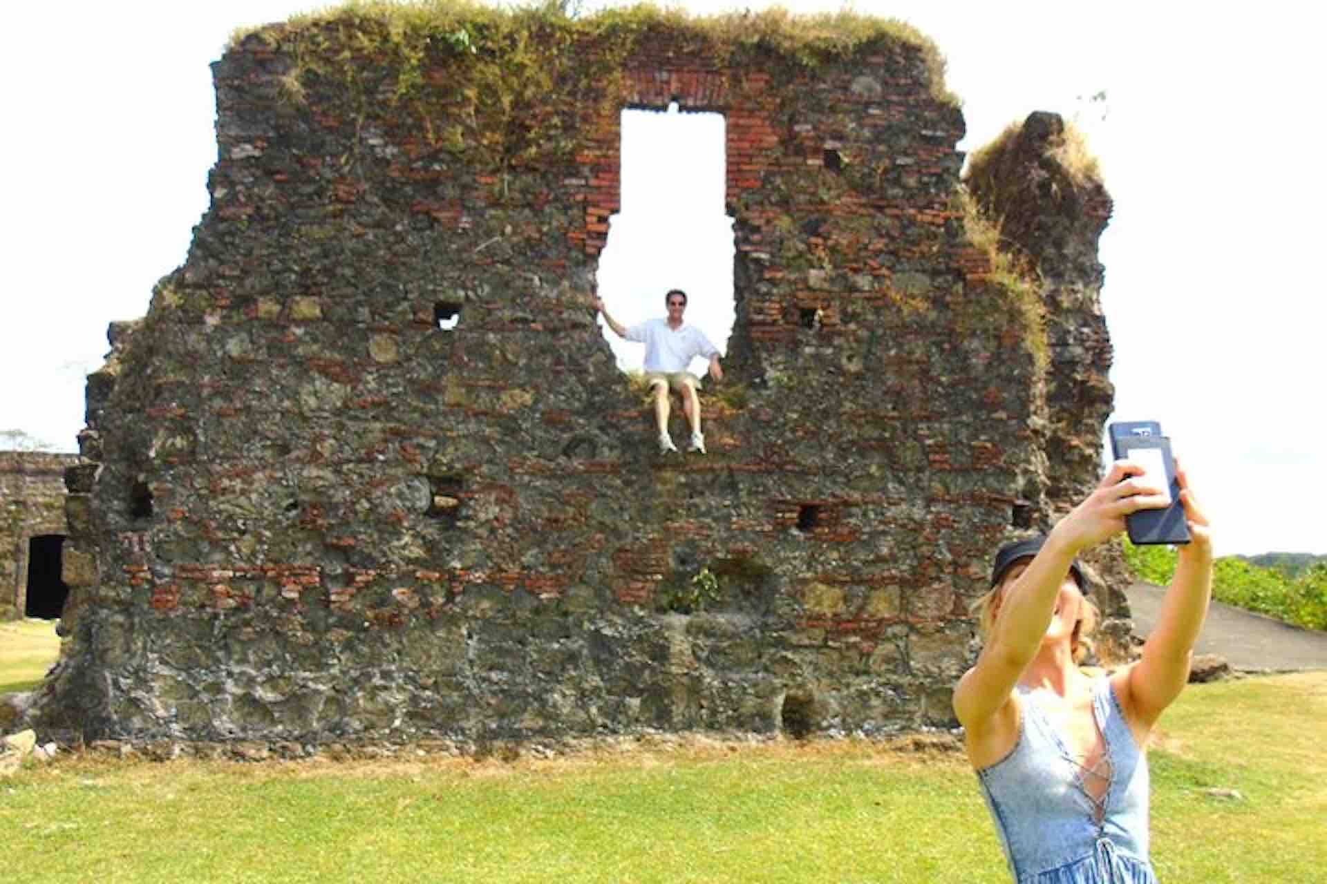Guests taking a selfie beside a weathered stone wall at Fort San Lorenzo on the Ocean to Ocean Panama Canal Tour