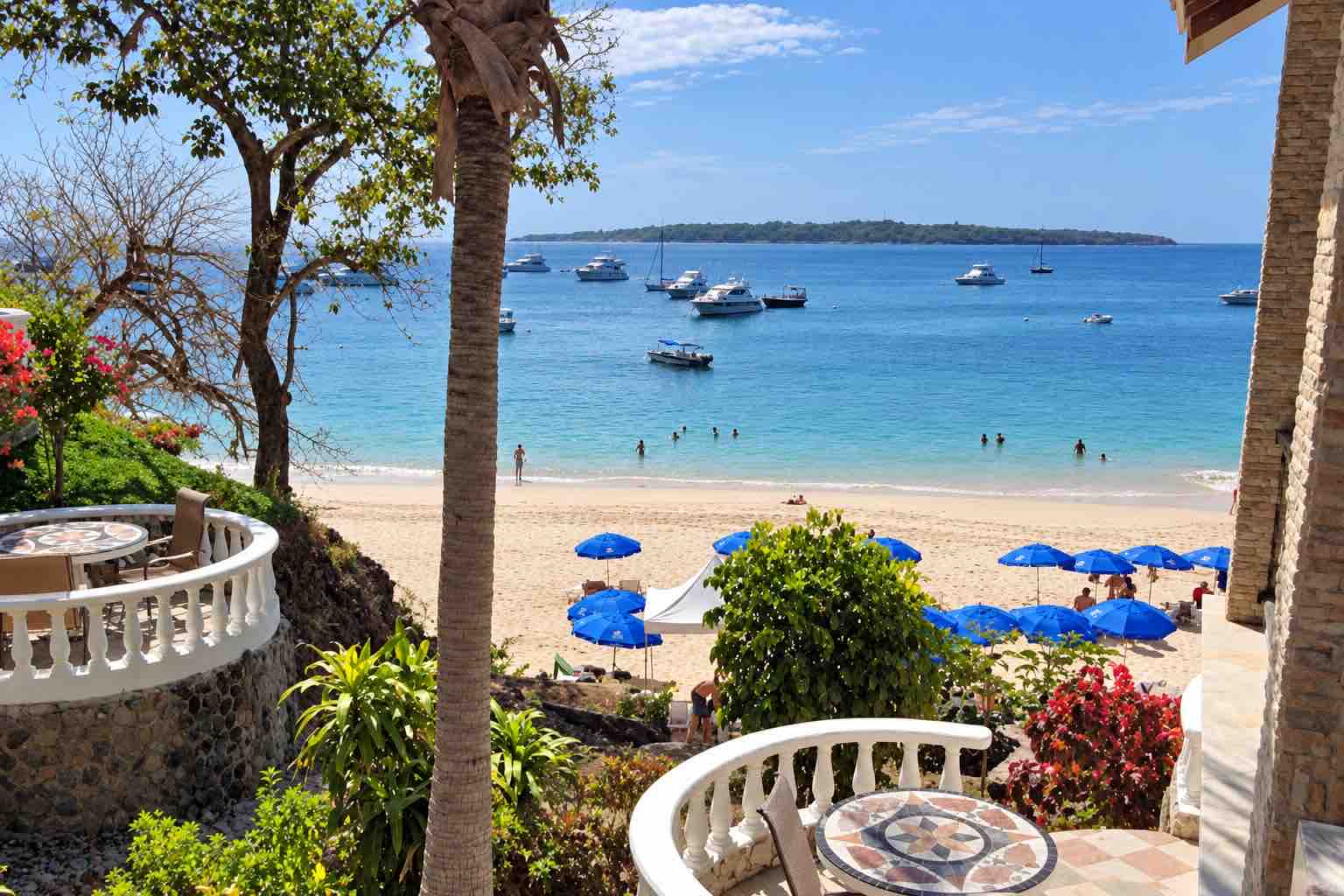 Mar y Oro Contadora – Balcony bay view Mar y Oro Contadora – White balcony railings and palms overlooking beach umbrellas and anchored boats