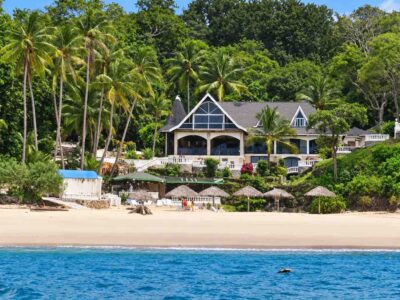 Mar Y Oro Contadora – Beachfront Property Mar y Oro Contadora – Hotel building with white terraces, palm trees and beach umbrellas