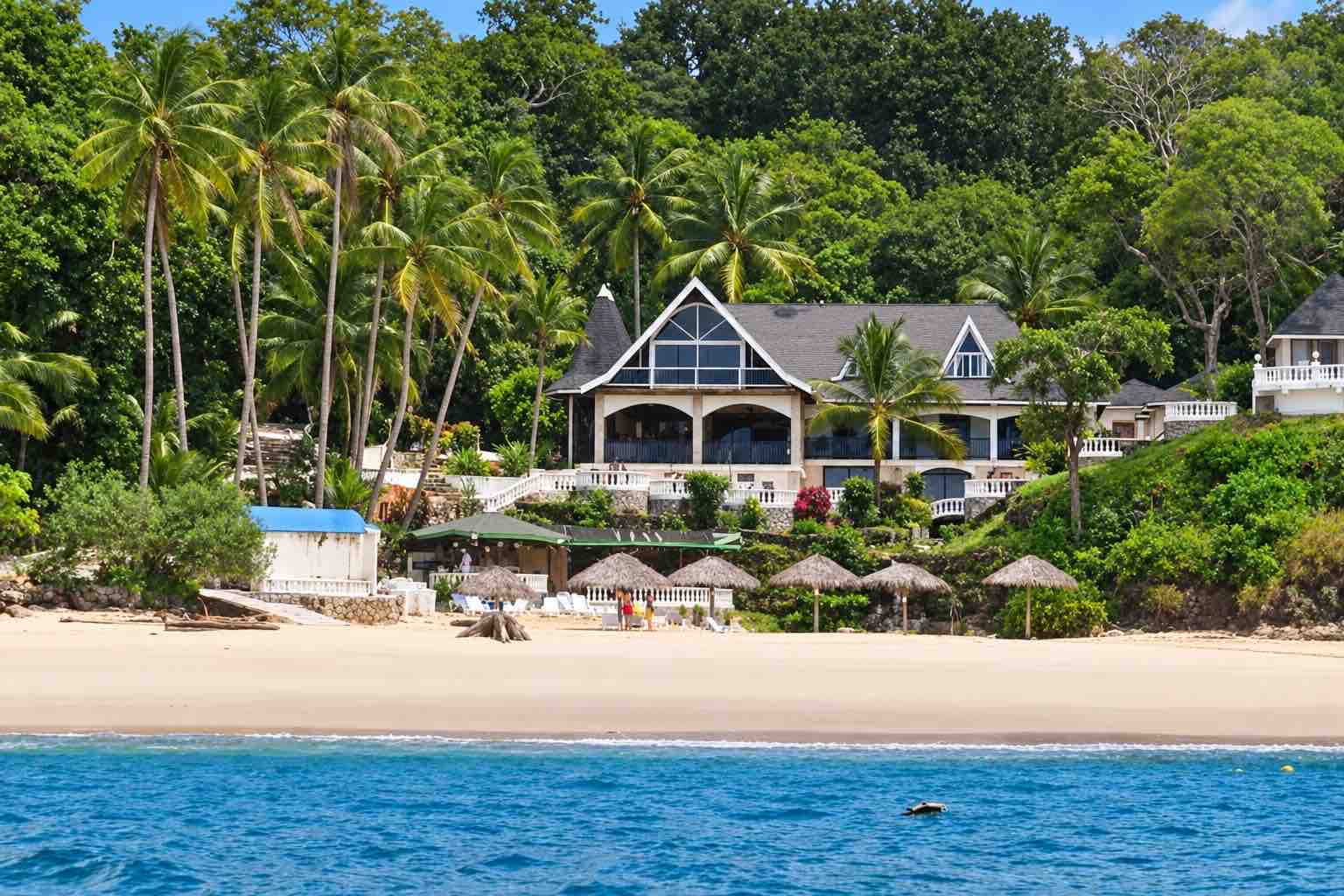 Mar y Oro Contadora – Hotel building with white terraces, palm trees and beach umbrellas