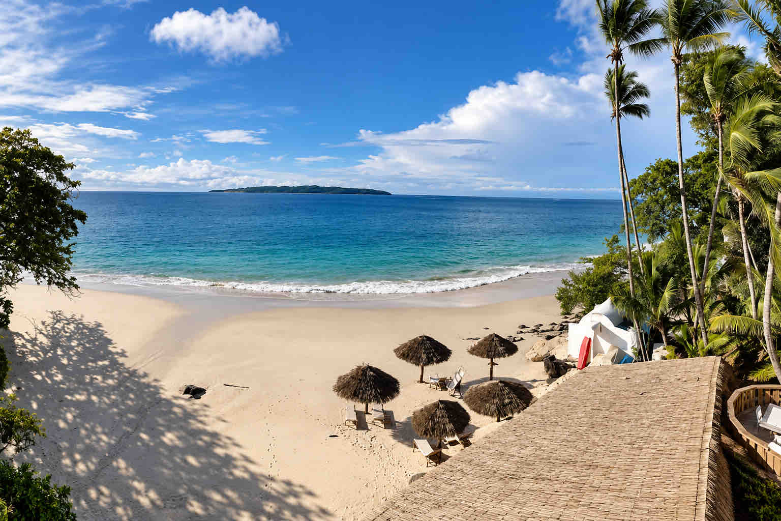 Terrace view of thatched beach umbrellas, palms and ocean at Mar y Oro Contadora