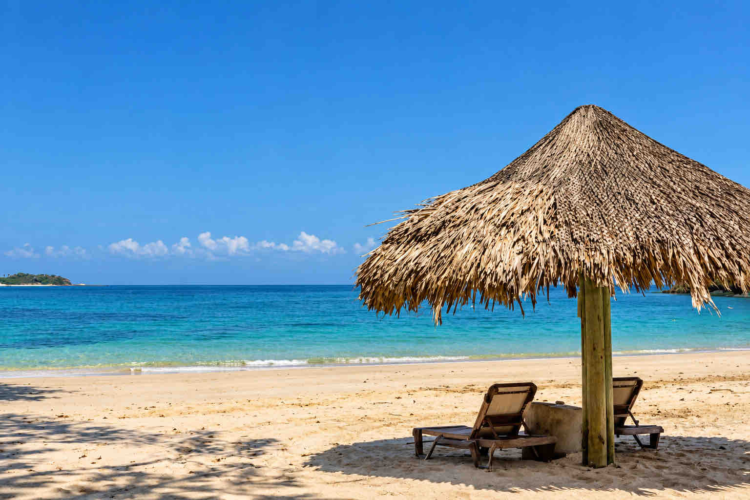 Thatched umbrella and two loungers overlooking the sea at Pimienta y Sal
