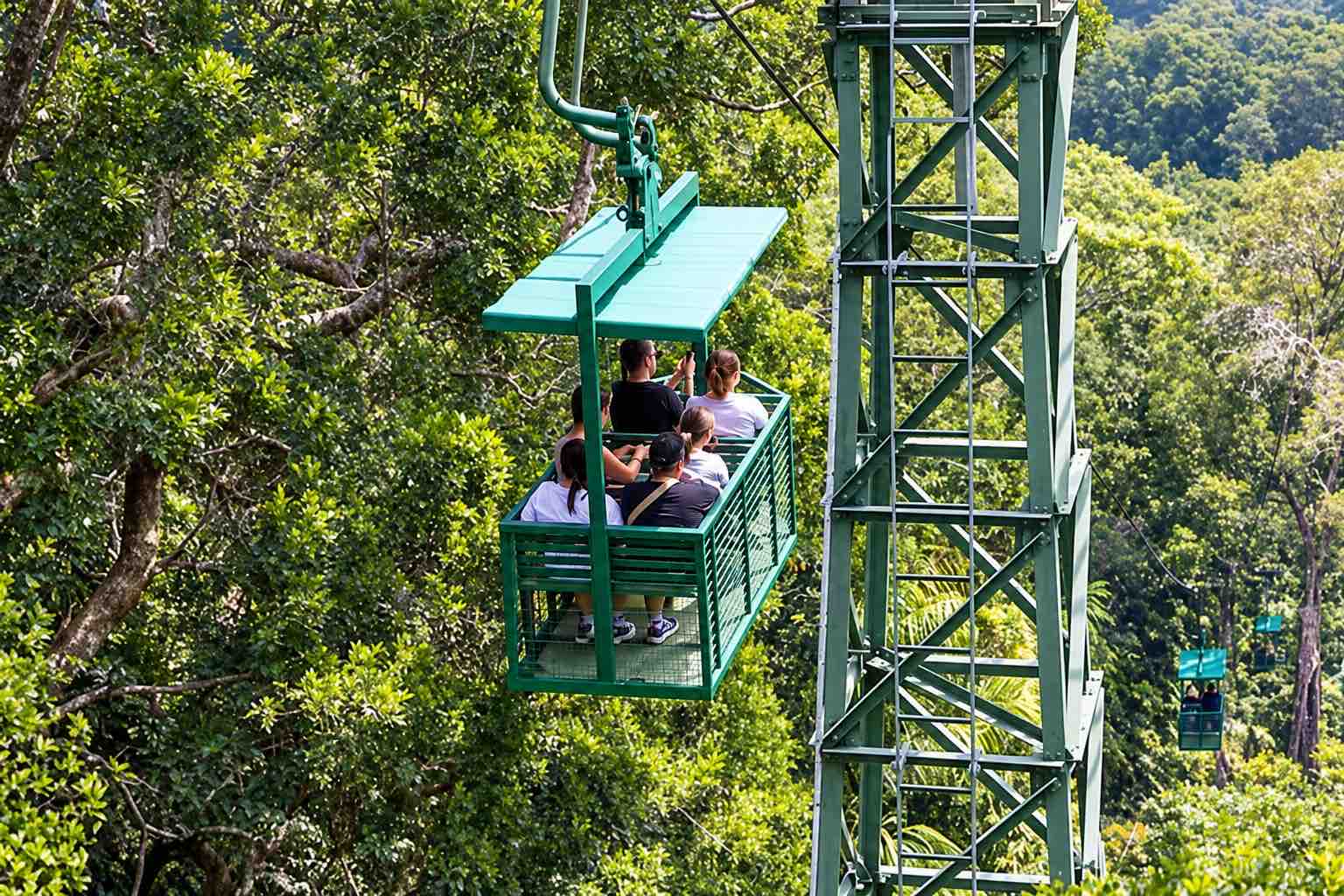 Gamboa Aerial Tram Panama Green aerial tram carrying passengers through dense rainforest beside a metal support tower in Gamboa, Panama