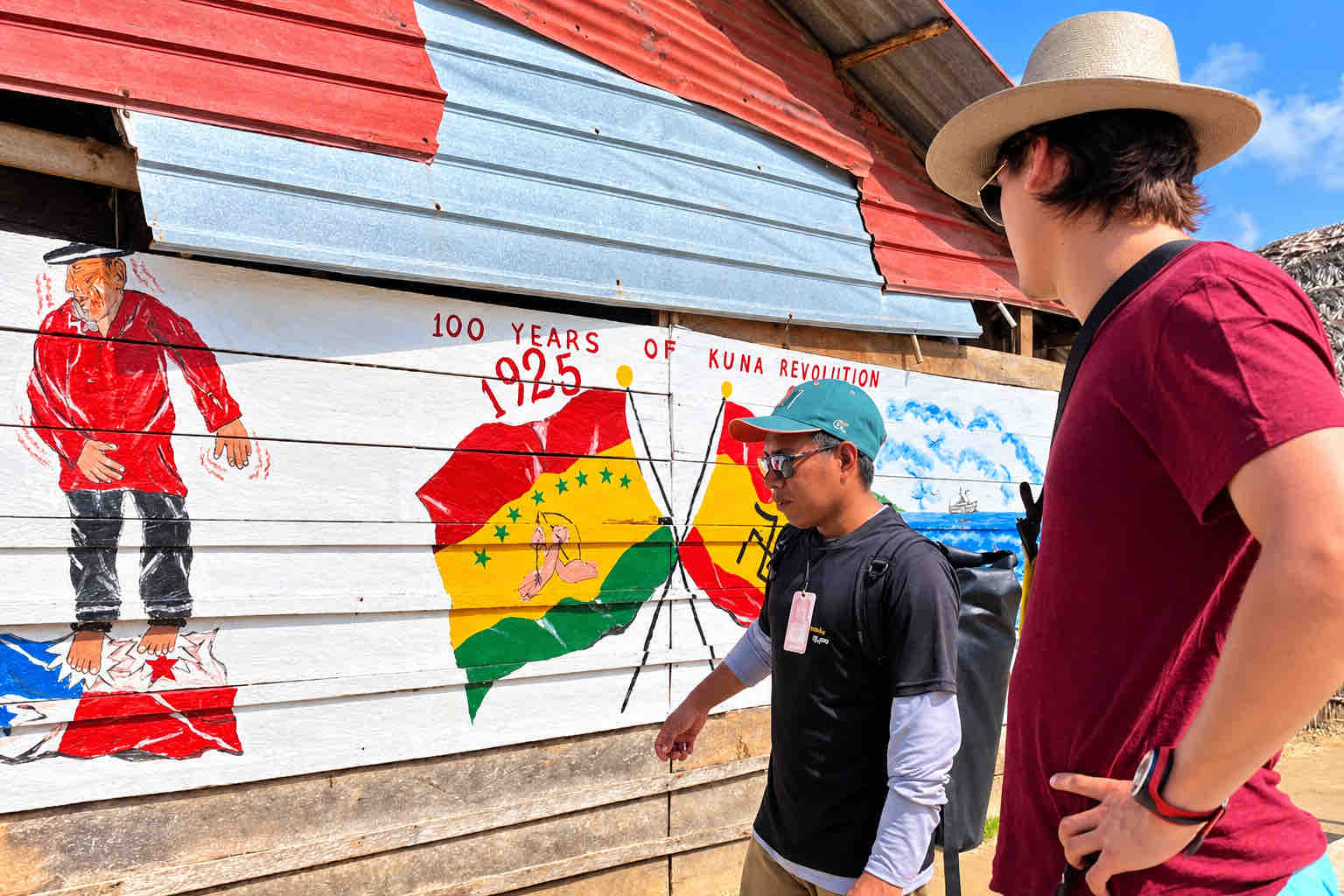 Visitor and guide looking at a painted mural on a community building