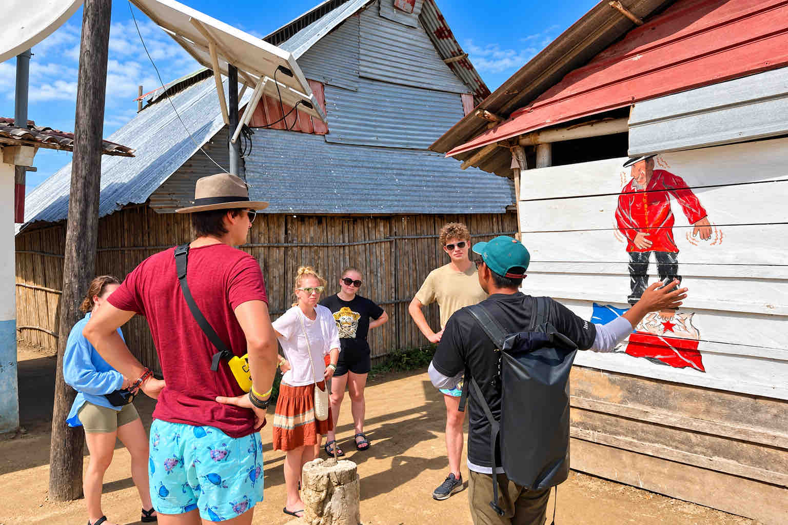 Guna Yala Tour – Community Walk Visitors and a local guide walking past wooden houses in a Guna community
