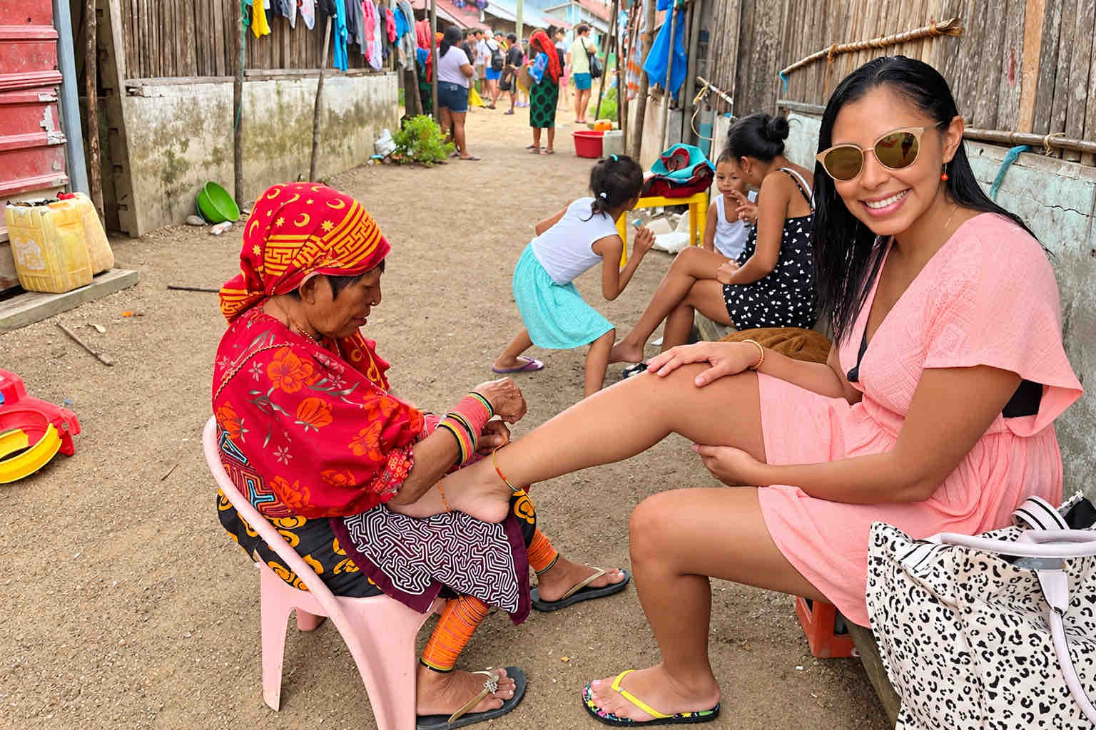 Smiling visitor receiving a beaded anklet from a Guna artisan