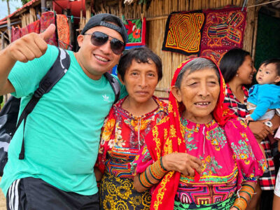 Visitor smiling with two Guna women in colorful traditional clothing during Guna Yala Tour