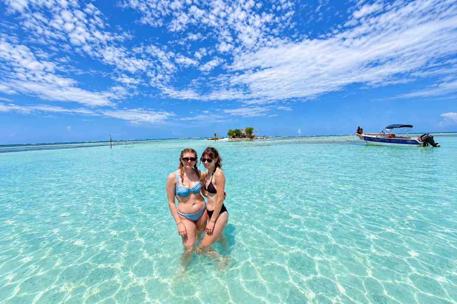 San Blas Day Tour Natural Pool Two friends standing together in turquoise shallow water beneath a blue sky at the San Blas Natural Pool