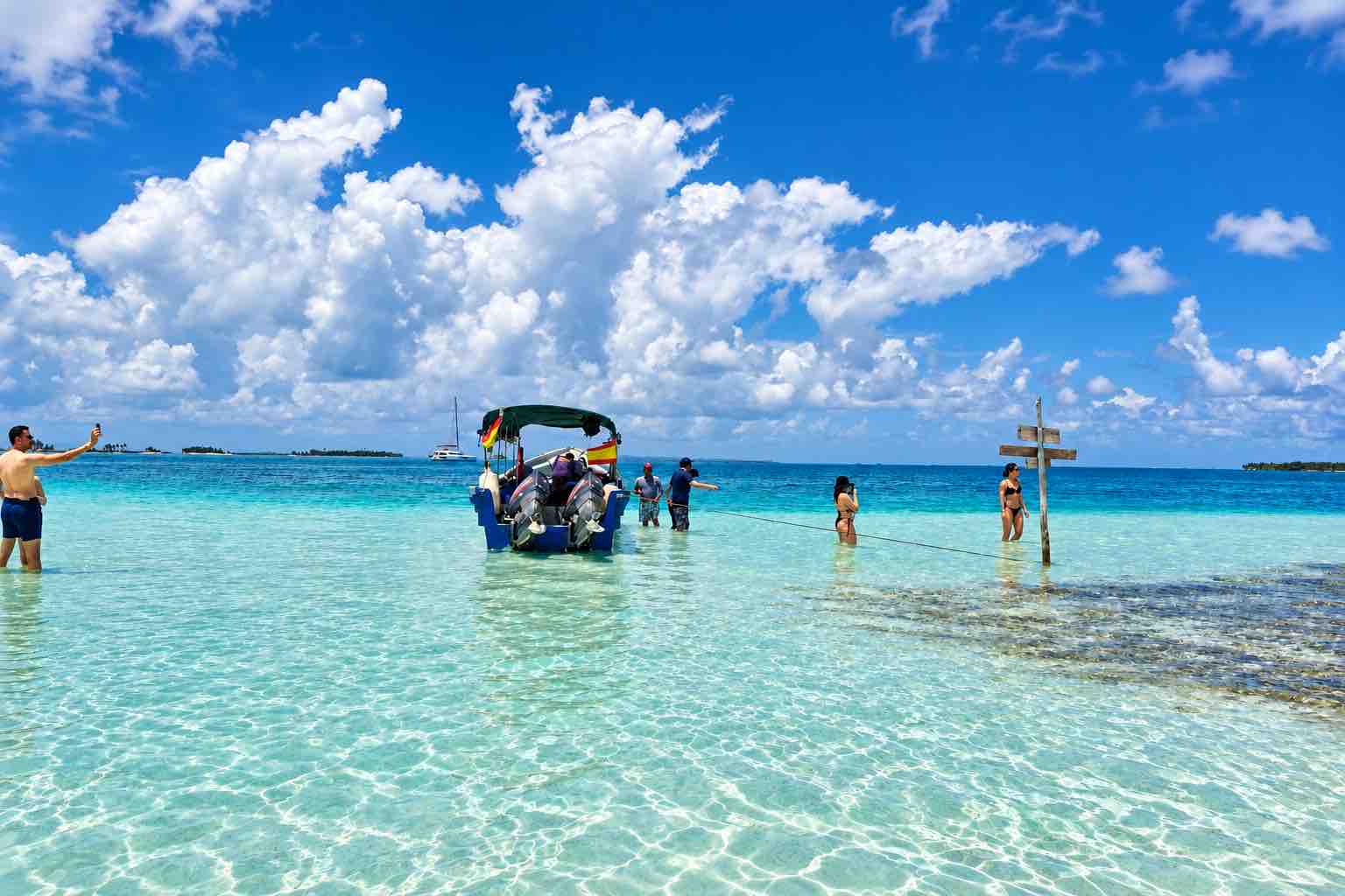 Tour boat and visitors in shallow turquoise water at the San Blas Natural Pool