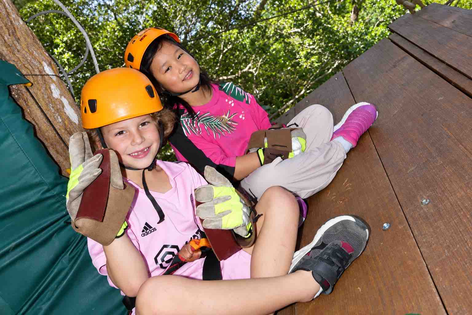 Two children wearing helmets and gloves on a wooden platform during Zipline Panama.