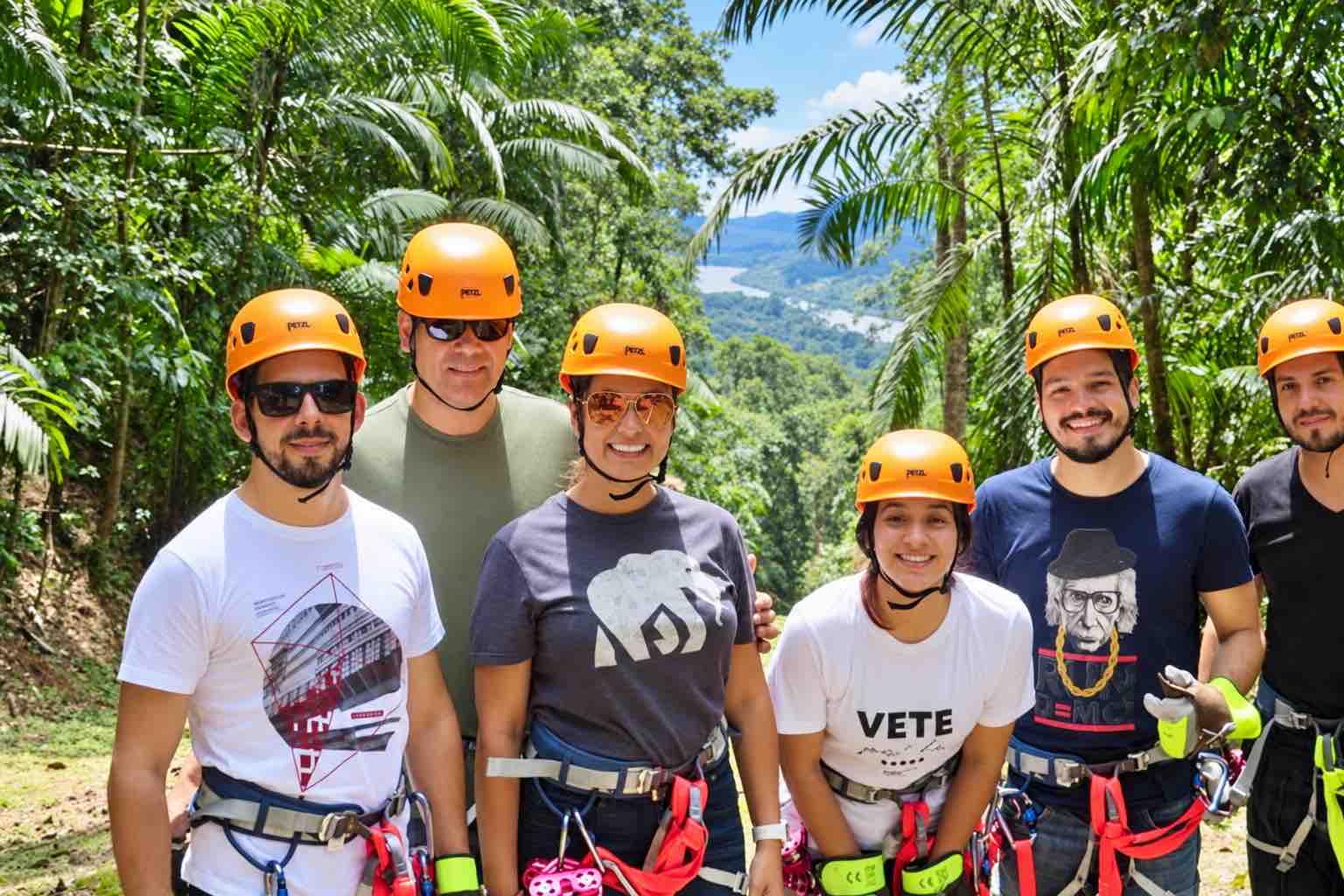 Guests wearing orange helmets and harnesses posing among palms on the Zipline Panama tour