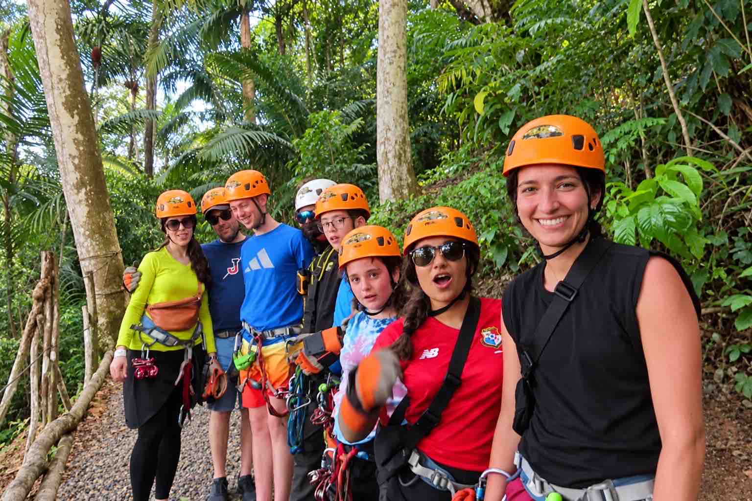 Guests in orange helmets and harnesses posing beside trees on the Zipline Panama tour
