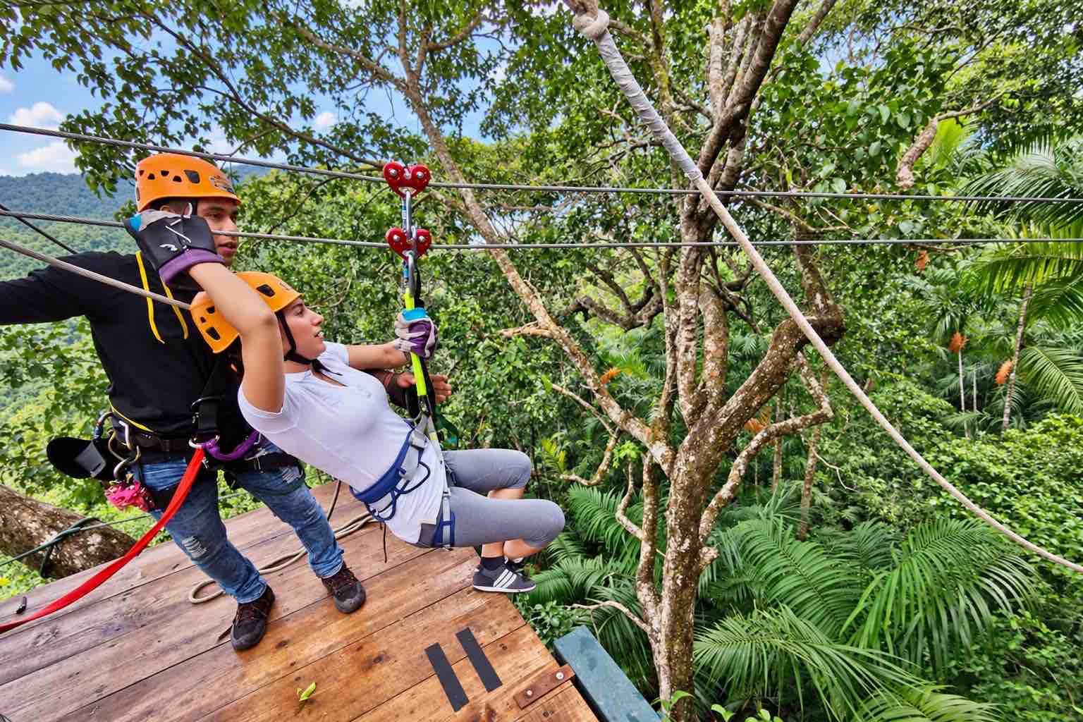Instructor assisting a helmeted guest at a wooden launch platform on the Zipline Panama circuit