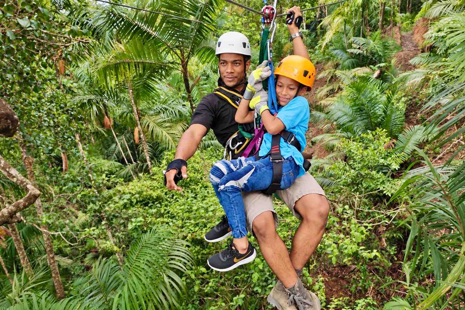 Instructor and child in helmets and harnesses riding together on the Zipline Panama circuit
