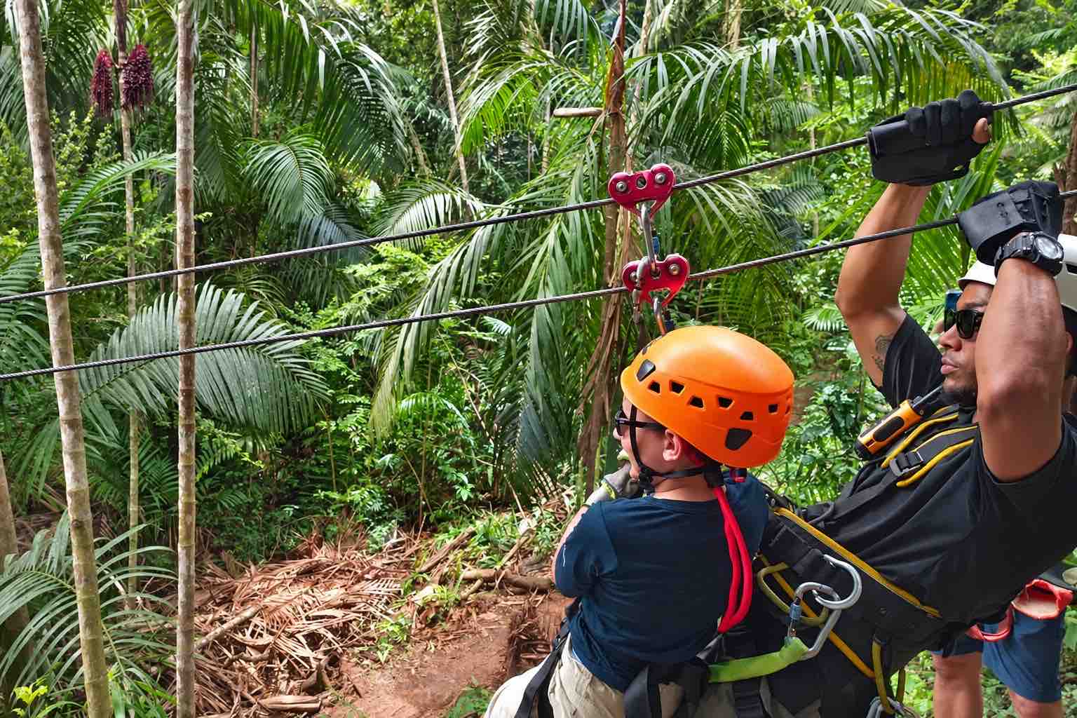 Instructor accompanying a child on the Zipline Panama course in Gamboa rainforest.