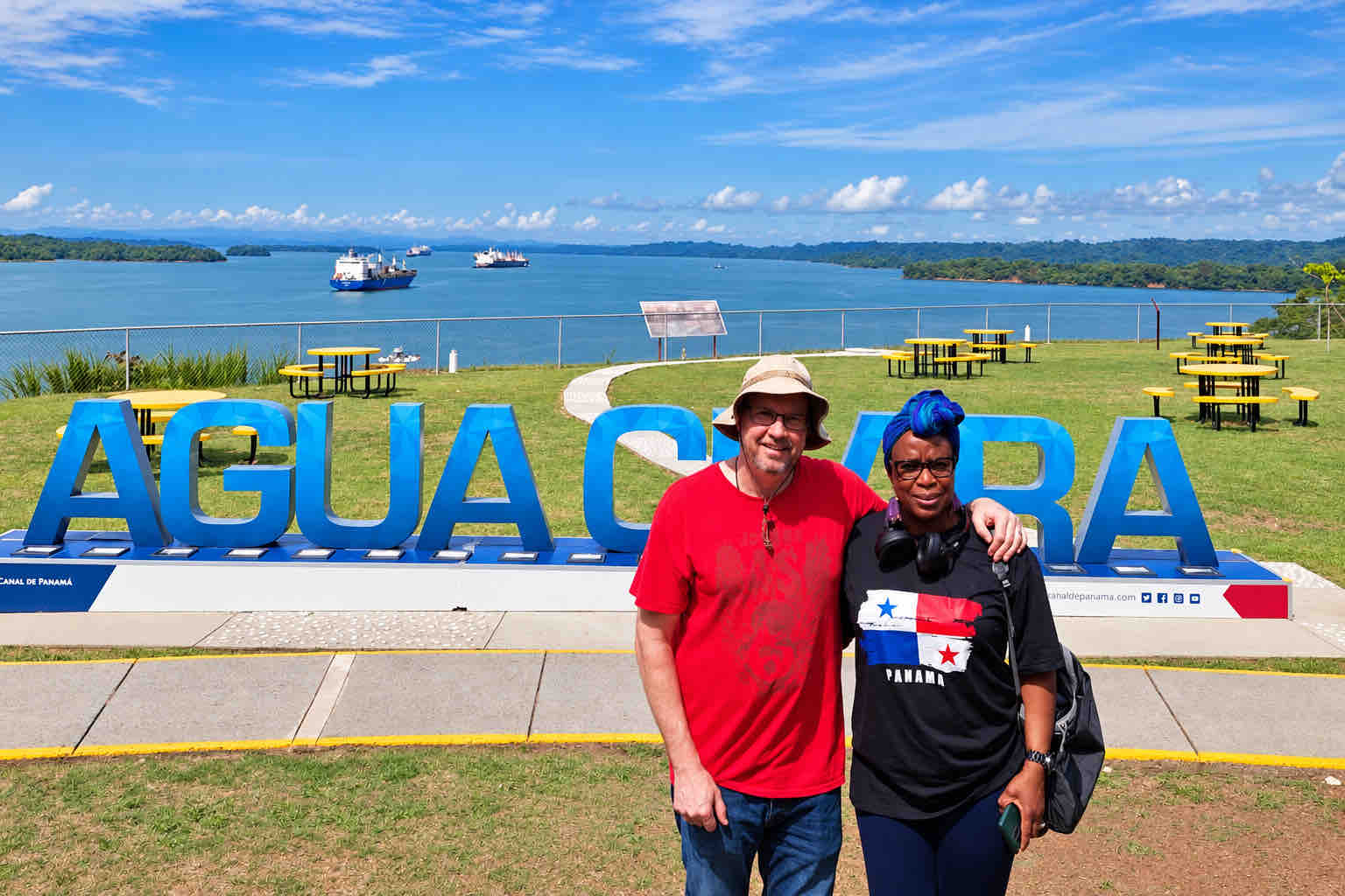 Two visitors posing by the Agua Clara sign overlooking the water.