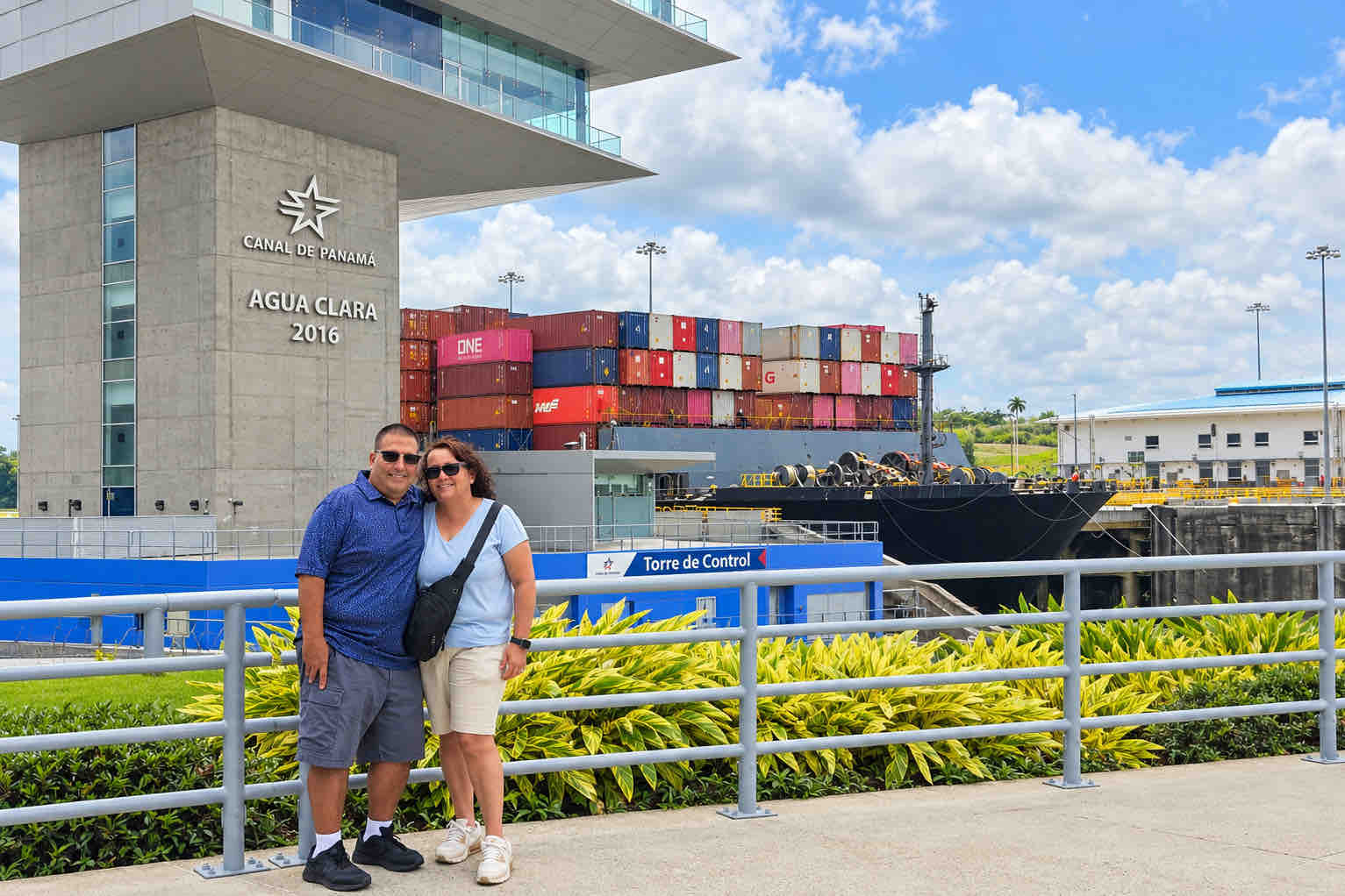 Couple at Agua Clara Locks with a container ship behind them on a Panama Canal Shore Excursion from Colón
