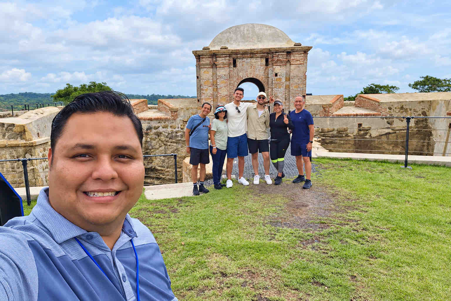 Guide and guests posing for a group selfie at a historic fort entrance on a Panama Canal Shore Excursion from Colón