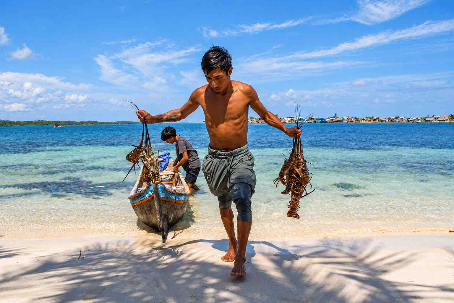 Fisherman carrying his catch along a sandy San Blas beach