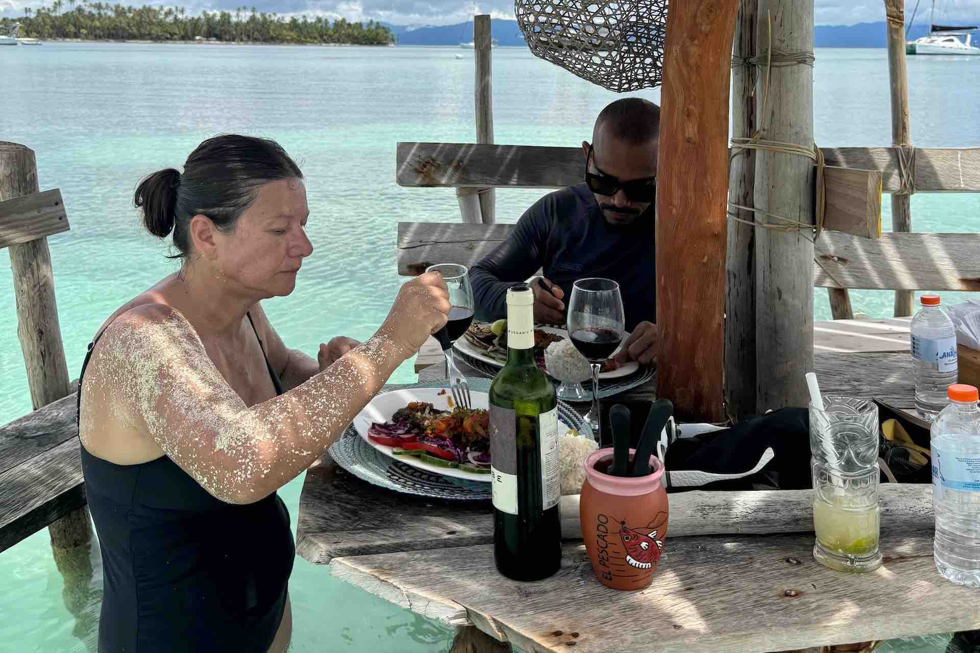 Guests eating at a wooden table overlooking San Blas waters