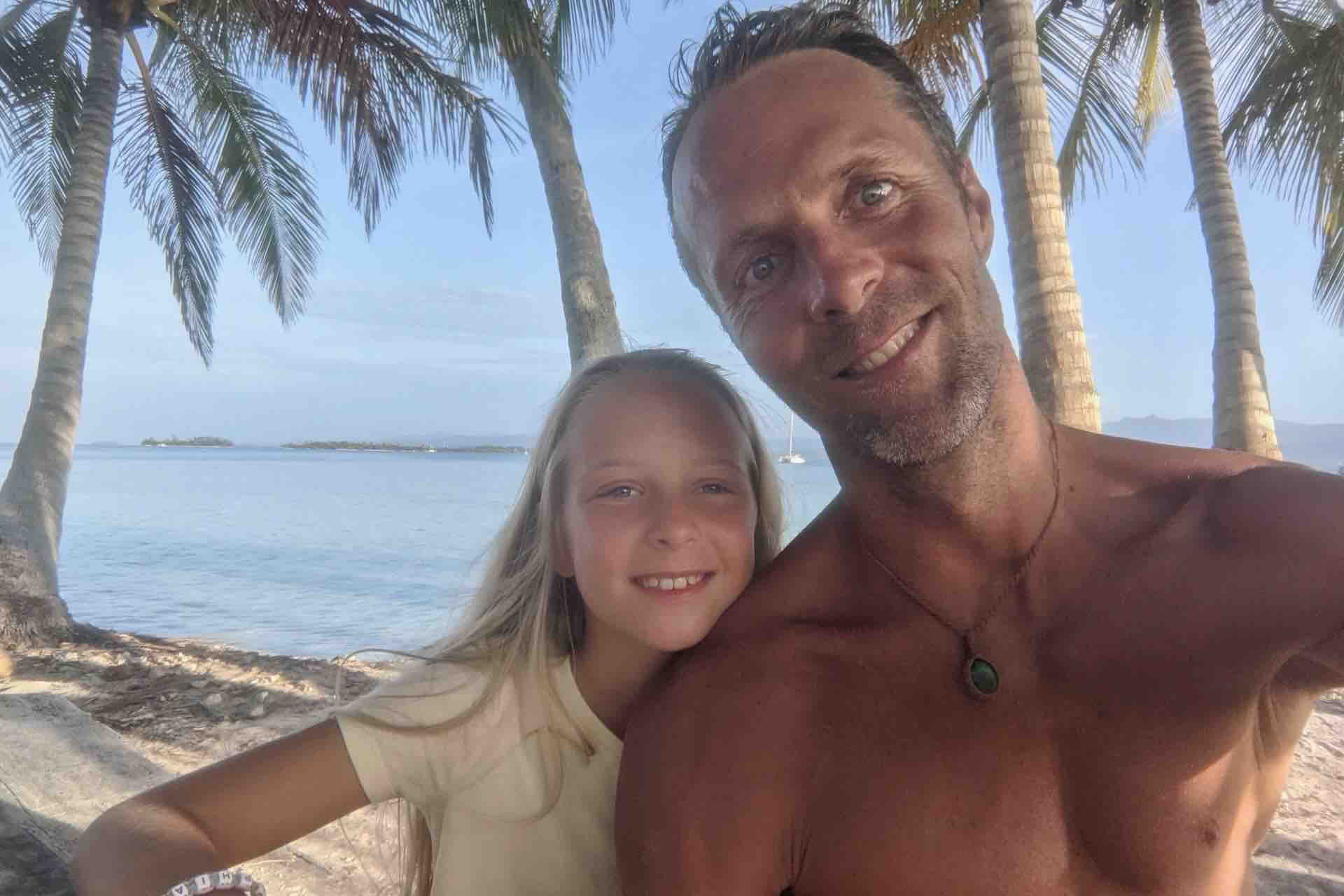 Man and child taking a selfie on a palm-lined San Blas beach